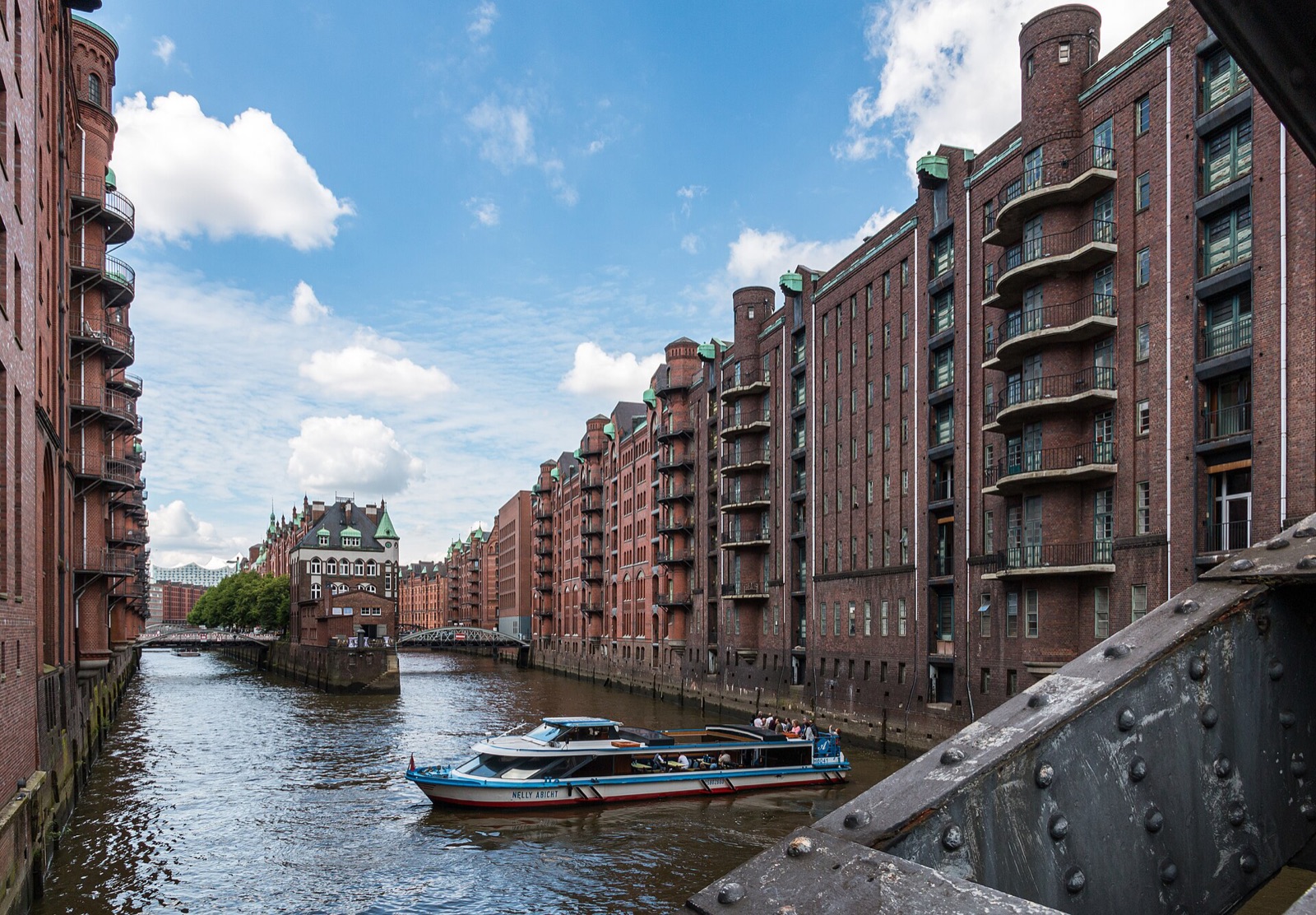 Brick warehouses of the Speicherstadt in Hamburg reflected in a canal under a blue sky with clouds