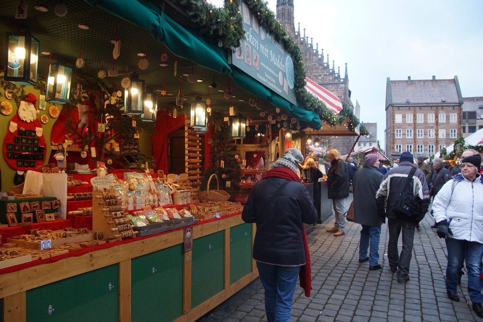 Rows of red and white striped stalls at the Christkindlesmarkt on the Hauptmarkt in Nuremberg with shoppers between them