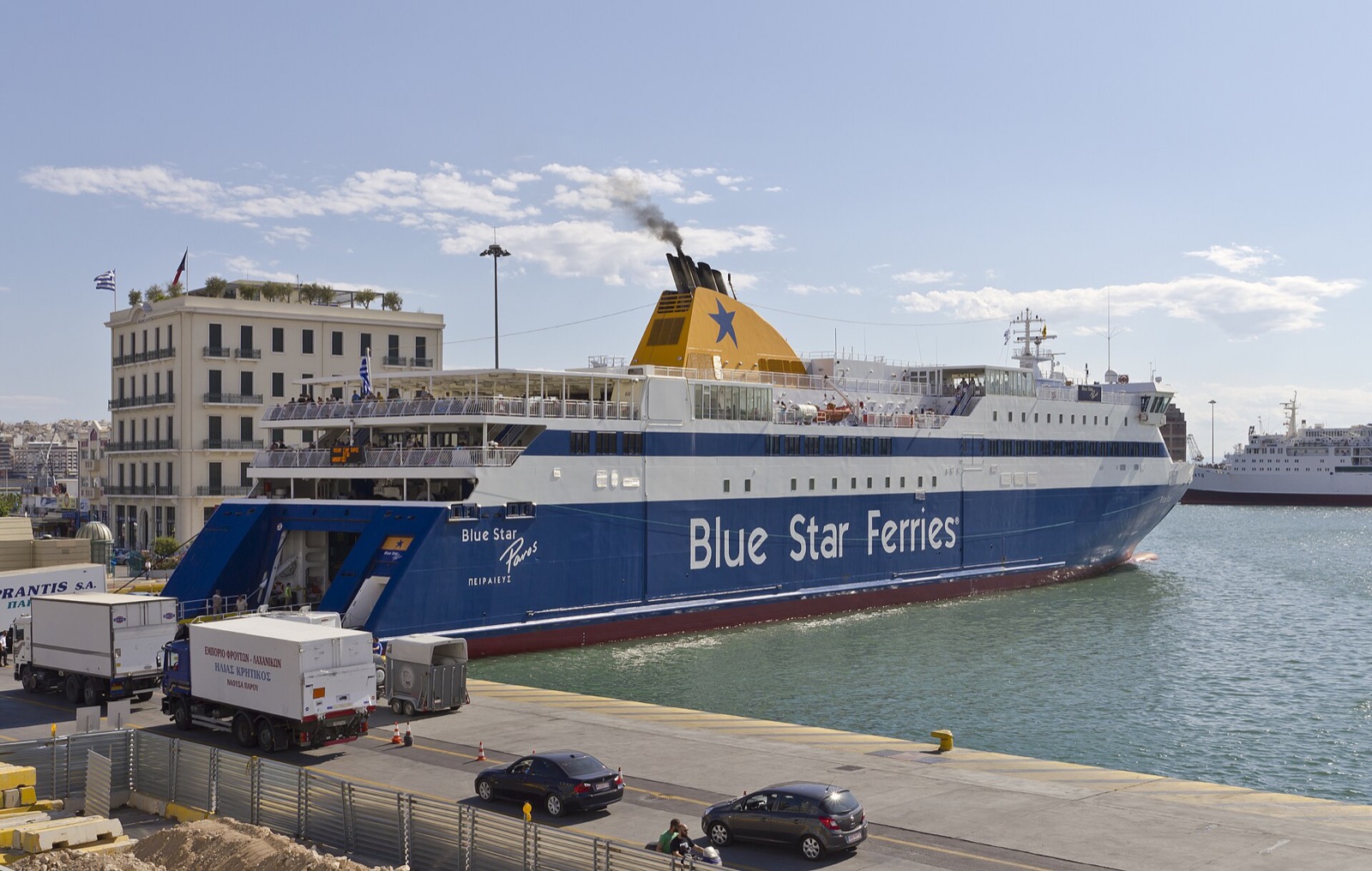 A Blue Star Ferries vessel moored at the port of Piraeus near Athens, with the town rising behind the quay