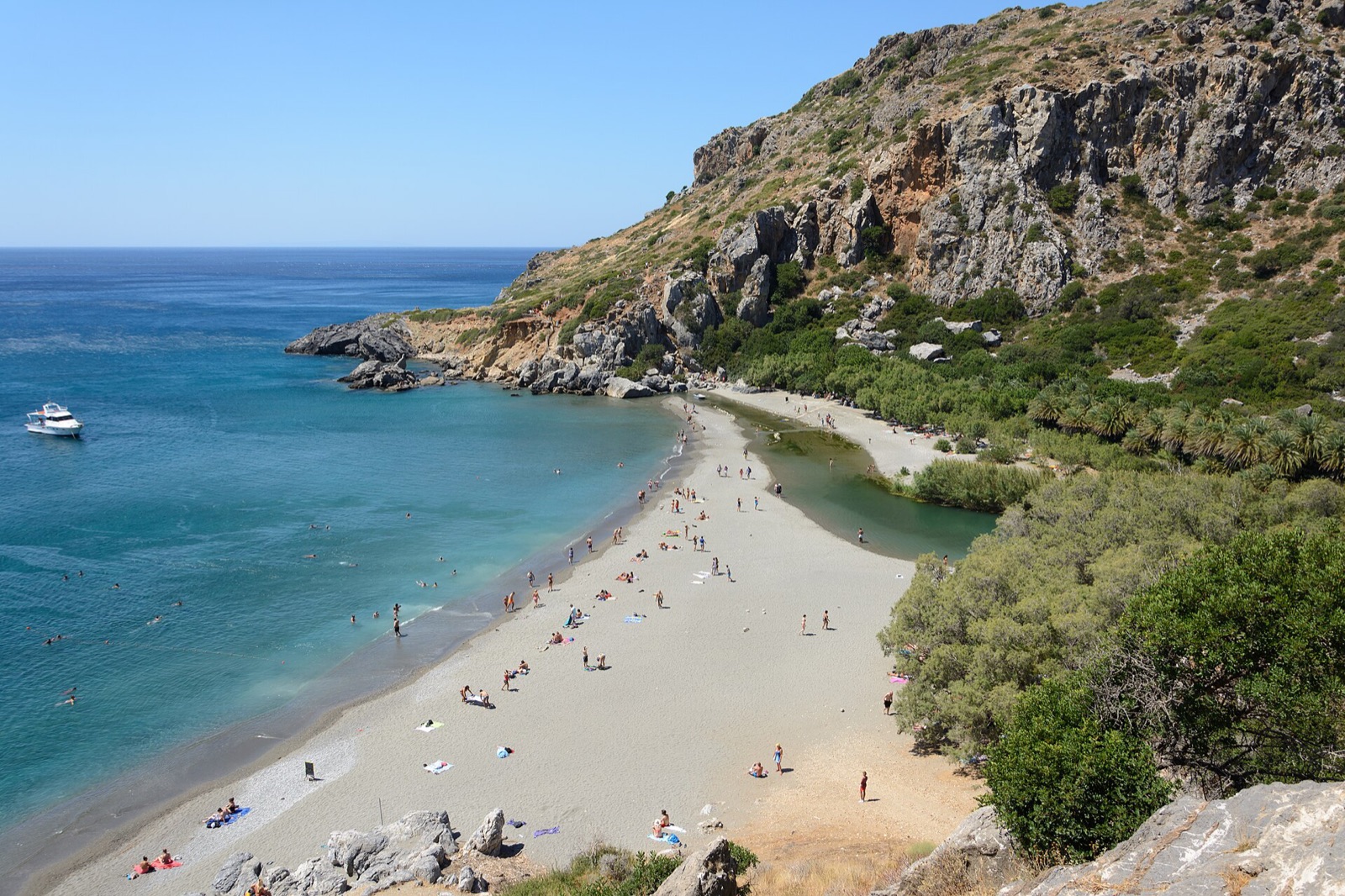 Preveli palm beach on the south coast of Crete, where a palm lined river meets a curved sand and pebble bay