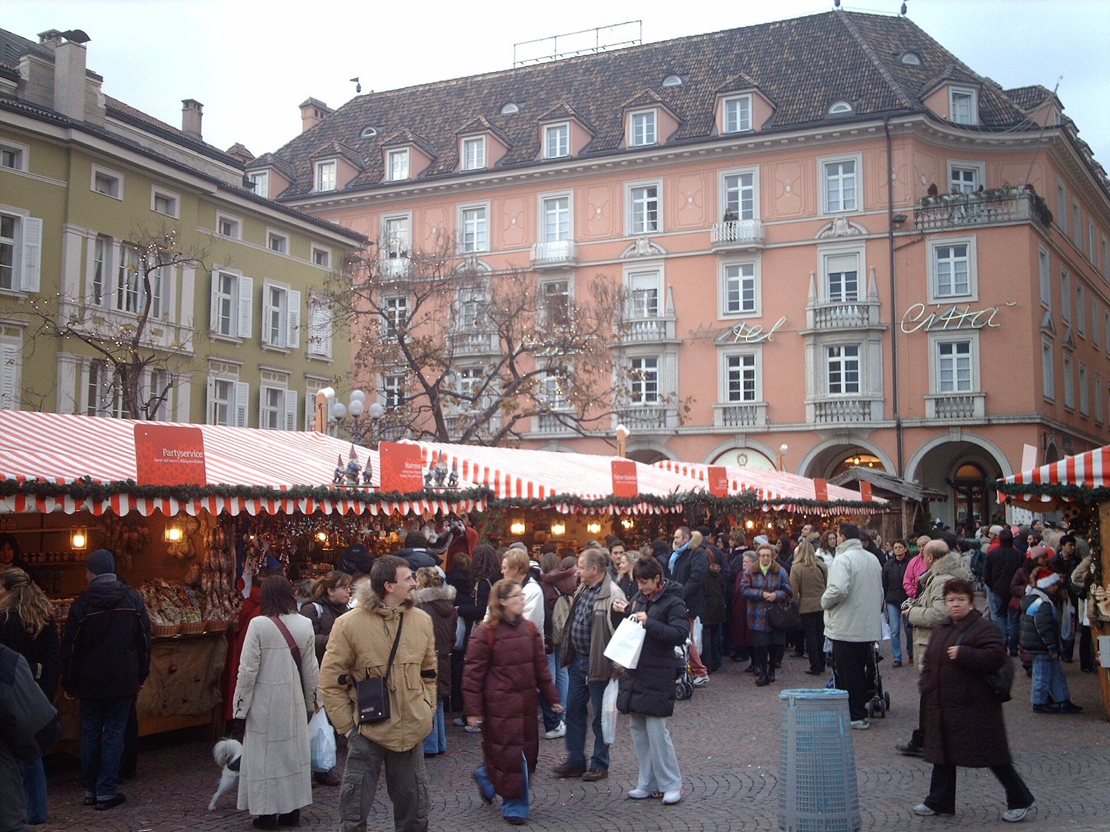The Christmas market in Bolzano in Alto Adige, with red and white striped stalls and crowds in front of pastel facades