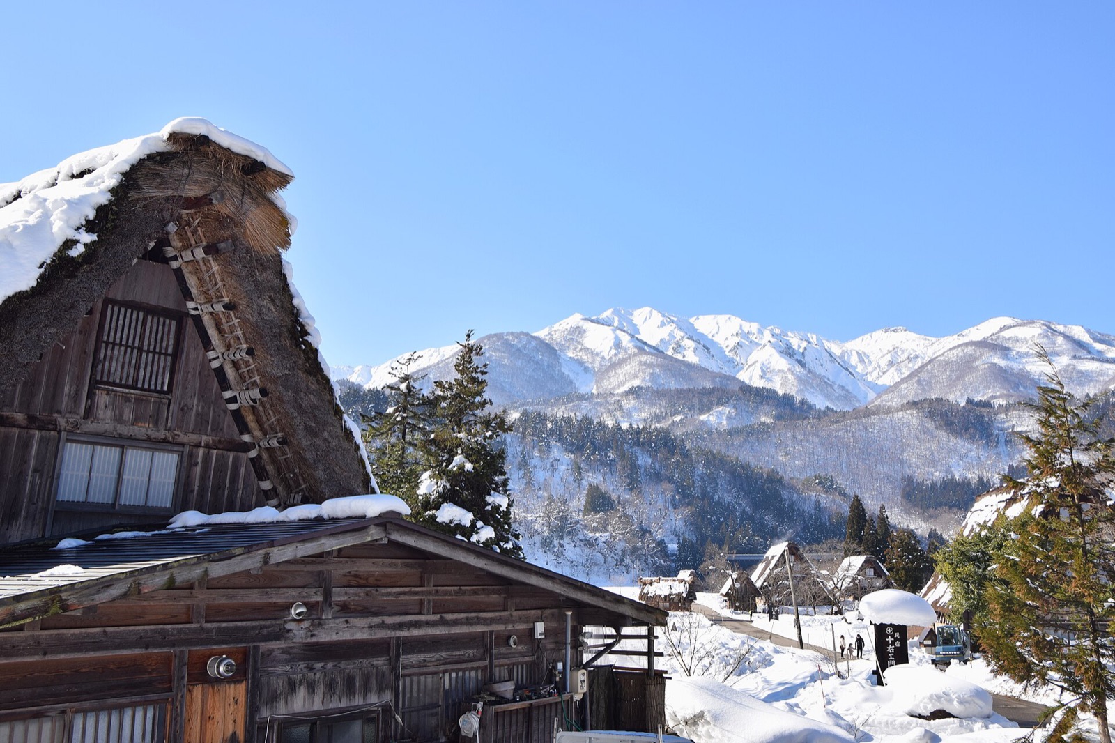A thatched gassho-style farmhouse under deep snow at Shirakawa-go in Gifu prefecture, with snow covered mountains behind