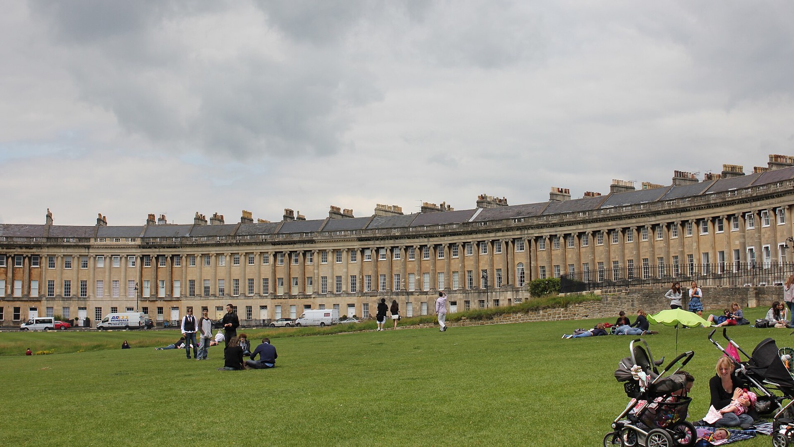 The Royal Crescent in Bath, England, with people on the lawn in summer